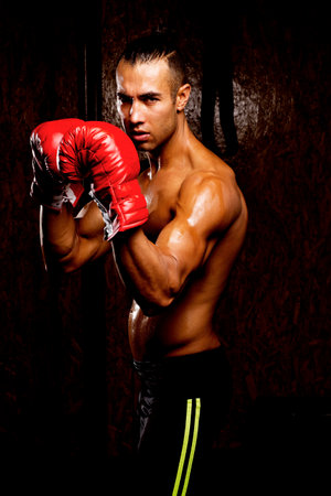 Young muscular man in gym boxing. Showing his muscles.の写真素材