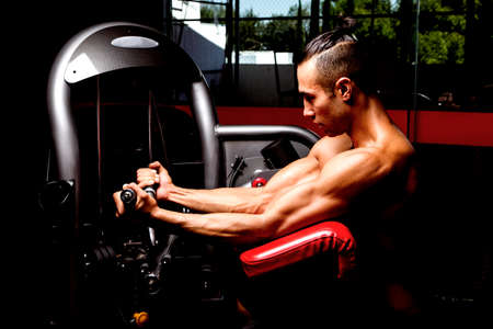 Young muscular man in gym doing exercise. Showing his muscles.