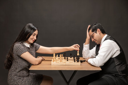 Elegant Couple man and woman playing on fine wooden chess board. Smiling woman winning the man.の写真素材