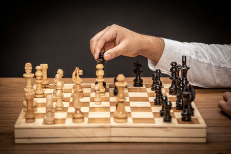 Man hand playing on chess board making the winning move.