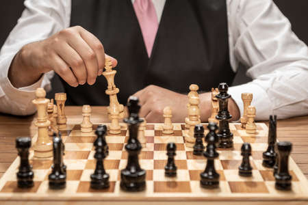 Man in elegant suit playing on fine wooden chess board.の写真素材