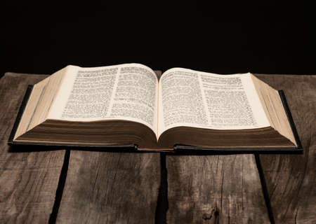 Holy bible open on rustic wooden table in dark night.の写真素材