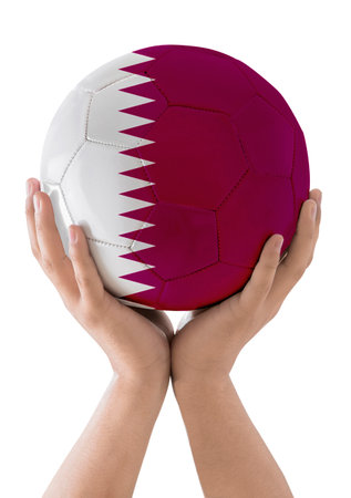 Man's hands raising a soccer ball with the flag of the Qatar team as a trophy on a white background.の写真素材