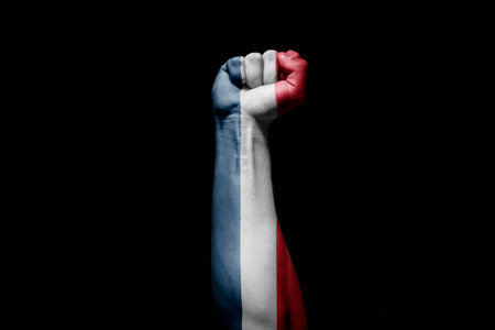 Strong man's hand in battle signal with Serbia flag on black background.の写真素材