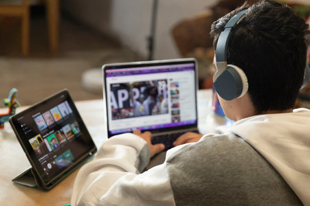 Young man with headphones sitting on the chair of his house studying and working at home with a...