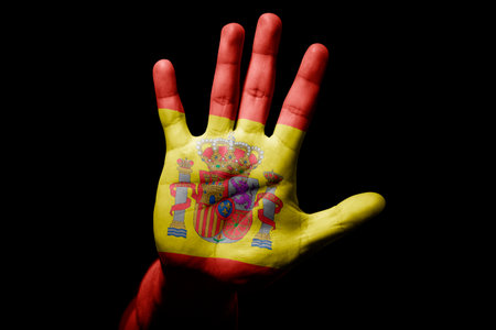 Rude man hand with flag of Spain in stop sign to anger, discrimination, racism, abuse on black background.の写真素材