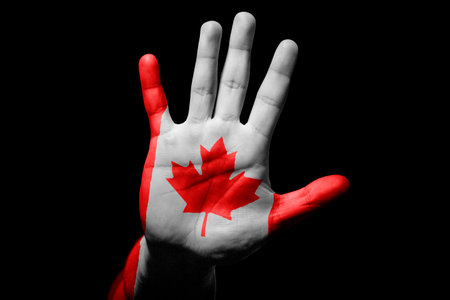 Rude man hand with flag of Canada in stop sign to anger, discrimination, racism, abuse on black background.の写真素材