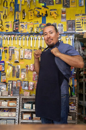 Handsome adult entrepreneur man in apron, with an expression of joy and happiness in his business full of hardware products.の写真素材