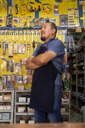 Handsome adult entrepreneur man in apron, with an expression of joy, happiness and pride in his business full of hardware products.の写真素材