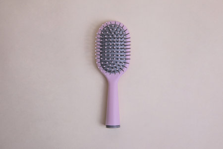 pink plastic comb with handle with gray details on a beige backgroundの写真素材