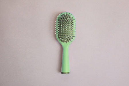 green plastic comb with handle with gray details on a beige backgroundの写真素材