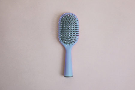 blue plastic comb with handle with gray details on a beige backgroundの写真素材