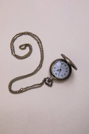 old pocket watch with train engraving on the cover, patinated brobce color, open with chain arranged...