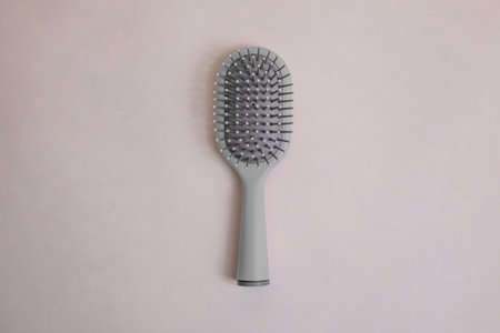 gray plastic comb with handle with gray details on a beige backgroundの写真素材