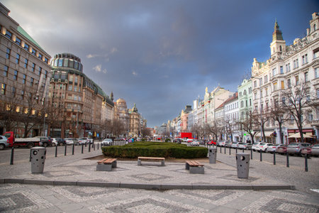 Beautiful front perspective view of Wenceslas Square in Prague, Czech Republic on a beautiful cloudy afternoon with its streets full of life, cars, pedestrians, businesses and commerceの写真素材