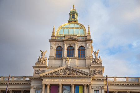 Detail of beautiful sculptures, dome and historical decorations that adorn the facade of the museum in Prague during sunsetの写真素材