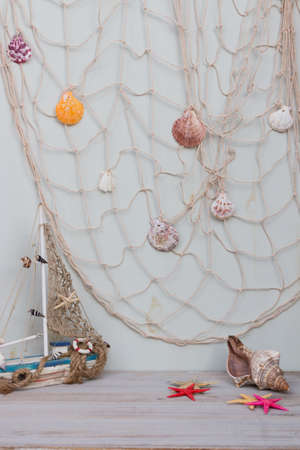 Set of boat, fishing net, starfish and seashells stand on a light gray background.の写真素材
