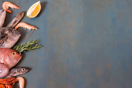 Fresh fish and seafood lay on blue wooden background with copy space.の写真素材