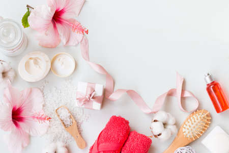 Top view on spa set with natural soap, cream, candles, towels and pink hibiscus on a white wooden background with copy space.の写真素材
