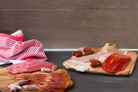 Chorizo, jamon and other Spanish meat appetizer on the black wooden background.の写真素材