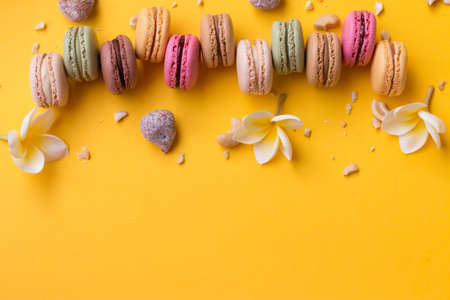 Bordure of delicious macarons with pieces of nuts on a yellow background.の写真素材