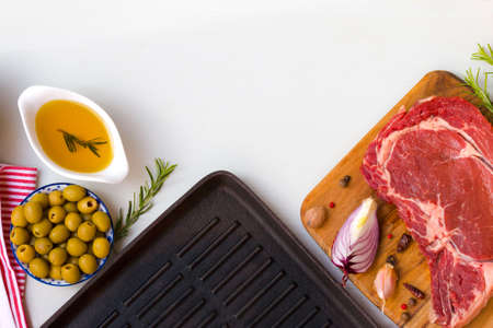 A fresh raw beef entrecote with ingredients to cooking taesty dinner and frying pan, top view with space for text.の写真素材