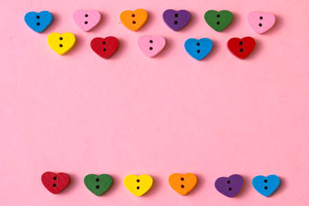 Frame of heart-shaped buttons with copy space on a pink background. Happy Valentine's day.