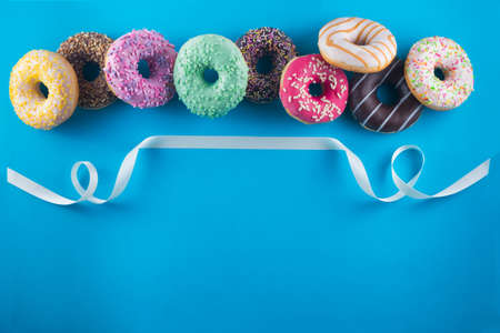 Tasty donuts with white ribbon on a blue background with a space for text.の写真素材