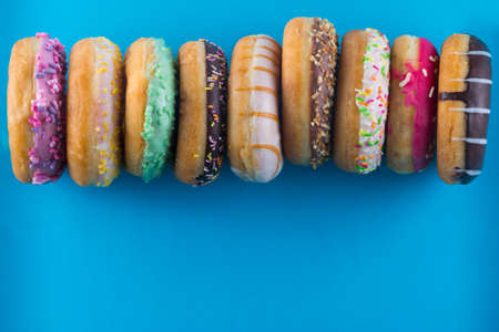 Bordure of different kinds of donuts on a blue background with copy space.の写真素材