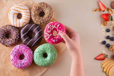 Someones hand holding sweet doughnut on light stone backgroundの写真素材