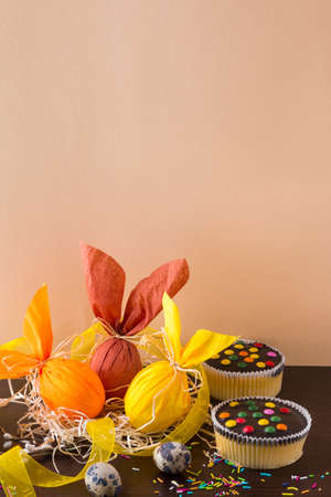 Easter eggs in the form of rabbit on a light brown background with cupcake. Holiday decorating.