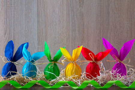 Bordure of Easter eggs in the form of rabbit on a light brown background with green ribbon . Holiday decorating.の写真素材