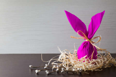 Easter egg in the form of rabbit in the nest with willow branch. Holiday decorating.の写真素材