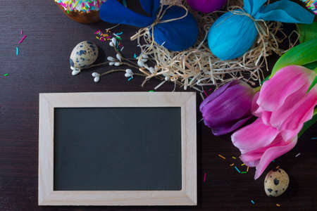 Easter decorating. Easter eggs in form of rabbit in the nest with with blackboard in a frame to write the text.の写真素材
