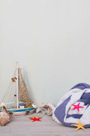 Miniature boat, starfish and seashells stand on a gray background. Towel in white and blue lines. Marine lifetime.の写真素材