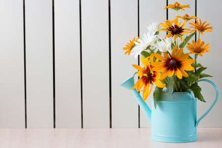 Yellow Rudbeckia , coneflowers, black-eyed-susans, flowers and other sumer flowers in a blue watering can.の写真素材