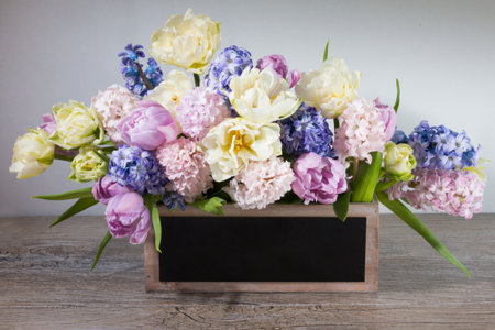 Bouquet of white tulips, pink and blue hyacinths in a wooden box with black copy space for text.の写真素材