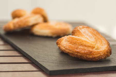 Pastry palmiers on a blackboard dish. Only the first is in focus.