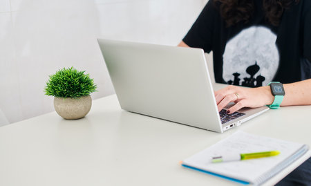 Girl working at home using a laptop and a notebook. Not visible faceの写真素材