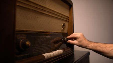 Man hand searching for the radio station on the vintage radio. High quality photo