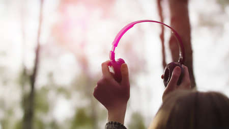 Silhouette of woman putting up the headphones in the forest. Sun light, sun lens flares, golden...