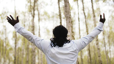 Black lives metters. African businessman with outstretche hands praying in the park. High quality...