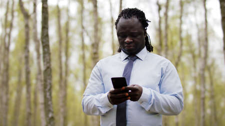 African man using smartphone in the nature. High quality photo