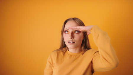 young caucasian woman with make up and eyelashes extension looking in the distance with hand above...