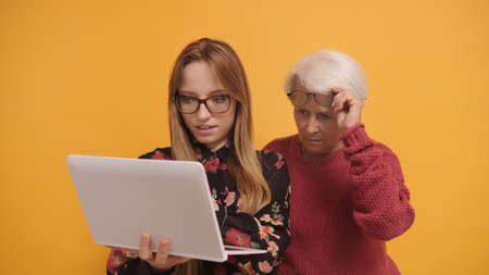 Young woman explaining to a senior lady how to use laptop. High quality photo
