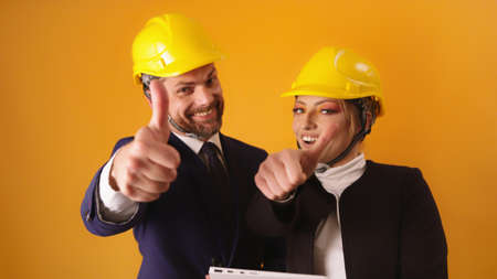 Portrait Of Two Architects Wearing Yellow Hard Hats Showing Thumbs-Up. High quality photo