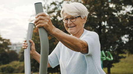 Wellbeing concept. Senior woman exercise using the equipment of an outdoor gym. High quality photo