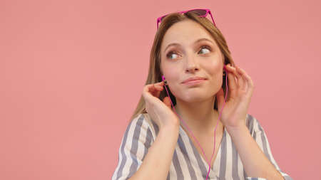 Beautiful young caucasian woman listening the music with the headphones. isolated on pink...