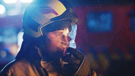 Portrait of the fireman in full uniform during the night rain.の写真素材