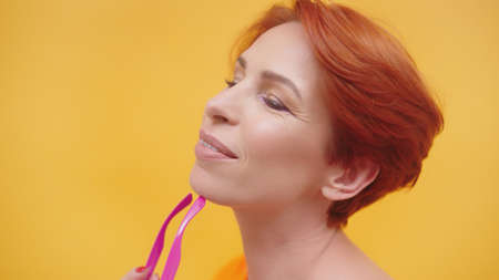 Portrait of red hair woman in her 40s isolated on yellow background. High quality photo